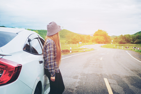 Relaxed happy woman traveler on summer roadtrip vacation on hatchback carの写真素材