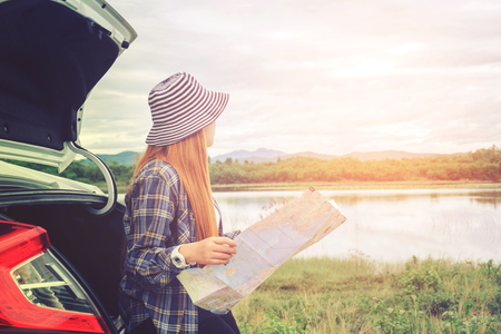 Happy beautiful girl traveling in a hatchback car with mapの写真素材
