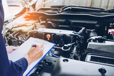 mechanic holding a clipboard of service order working in garage. Repair service.の写真素材