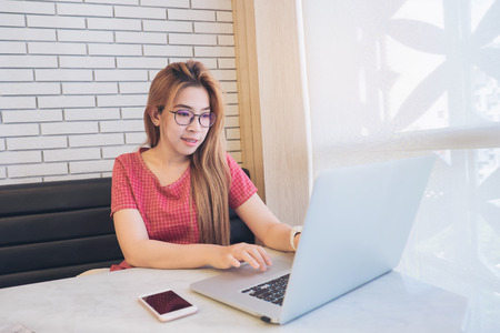 Asian girl working at a coffee shop with a laptop.female freelancer connecting to internetの写真素材