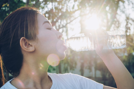 Fitness beautiful woman drinking water and sweating after exercisingの写真素材