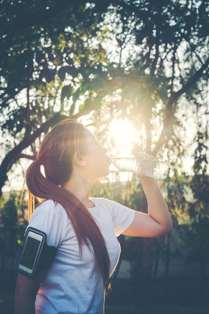 Fitness beautiful woman drinking water and sweating after exercisingの写真素材