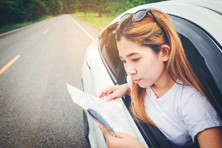 Happy beautiful girl traveling in a hatchback car with mapの写真素材
