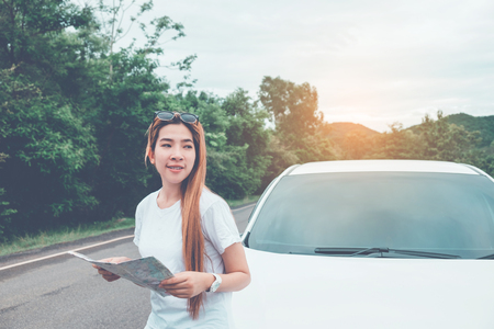 Happy beautiful girl traveling in a hatchback car with mapの写真素材