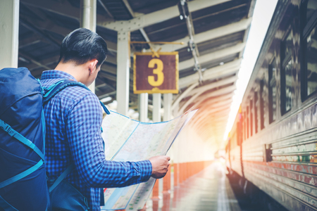 Traveler man with map and waits train on railway platformの写真素材