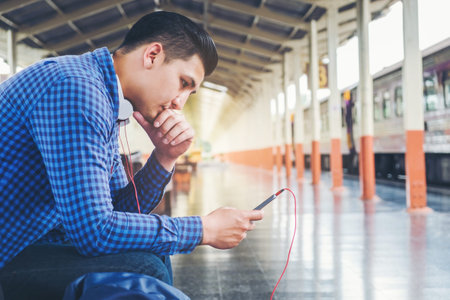 Traveler Man using tablet and phone waiting for train on the station