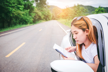 Relaxed happy woman traveler on summer roadtrip vacation on hatchback carの写真素材