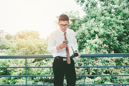 Businessman  Using Mobile Phone Hand holding  Coffee cup outdoorの写真素材