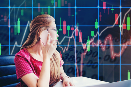 Asian businesswoman sitting on working space and looking the Stock market exchange information and Trading graphの写真素材