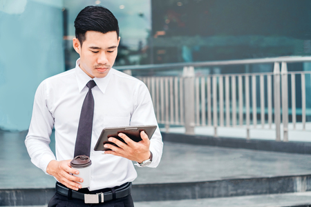 Businessman  With Coffee Using Digital Tablet at city outside officeの写真素材