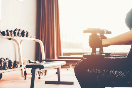 Asian sports woman doing exercises with dumbbell weights in gymの写真素材