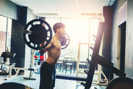 Fitness young Man lifting barbells looking focused working out in  gymの写真素材