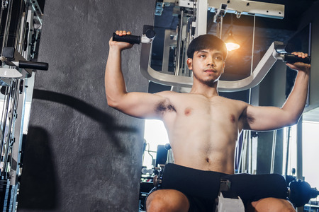 Fitness man exercising at the gym on a machine strong bodybuilder doing heavy weight exerciseの写真素材