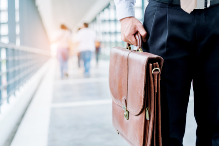 Businessman holding a briefcase travellers walking outdoorsの写真素材