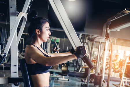 Asian young fitness woman execute exercise with exercise-machine in gymの写真素材