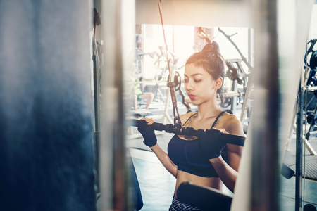 Asian young fitness woman execute exercise with exercise-machine in gymの写真素材