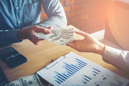 Hand giving money United States Dollars bills ,Hand receiving money from businessmanの写真素材