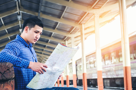 Tourist backpacker using map to travel at train stationの写真素材