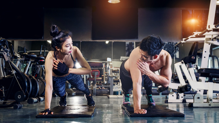 Fitness young people doing pushups in a gym looking face happy exerciseの写真素材