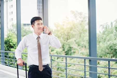 Professional businessman Travel using smartphone talking on his phone smiling happy outside walking inside in airportの写真素材