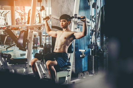 Fitness man exercising at the gym on a machine strong bodybuilder doing heavy weight exerciseの写真素材