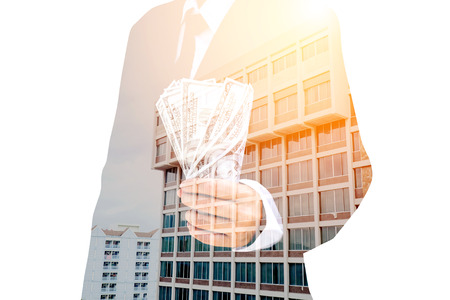 Double exposure of a businessman and a city Holding Dollar billsの写真素材