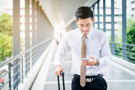 Professional businessman Travel using smartphone smiling happy outside walking inside in airportの写真素材