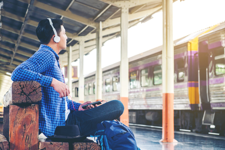 Travel man using mobile phone at train stationの写真素材