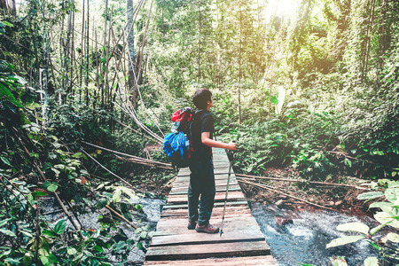 Tourist trail hiking in the forest Traveler Man with backpack crossing the mountain river in forestの写真素材