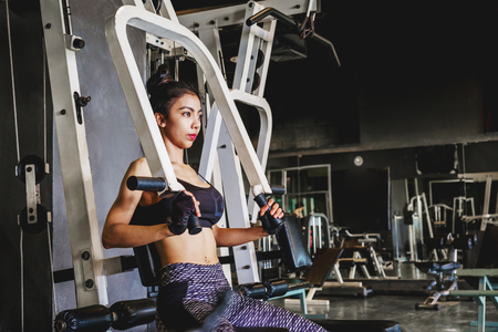 Asian young fitness woman execute exercise with exercise-machine in gymの写真素材