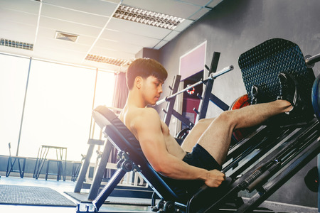 Fitness young man exercising using rowing machine in the gymの写真素材