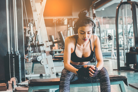 Fitness girl using smartphone and Headphones in fitness gymの写真素材