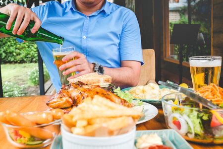 Young asian man drinking beer and eatting foods happy while enjoying homeの写真素材