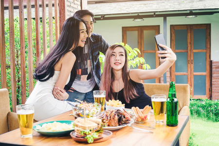 Group of friends are taking selfie and eating food are happy enjoying in homeの写真素材