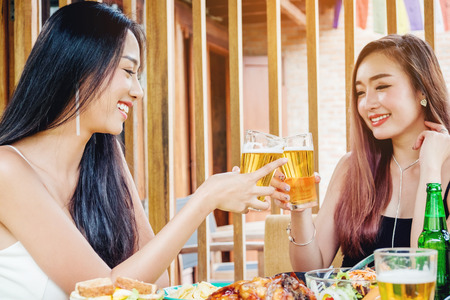 Young asian women drinking beer and clink glasses happy while enjoying home partyの写真素材