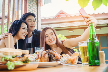 Group of friends are taking selfie and eating food are happy enjoying in homeの写真素材