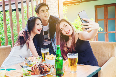 Group of friends are taking selfie and eating food are happy enjoying in homeの写真素材