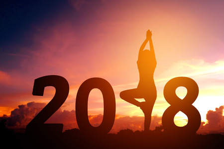Silhouette young woman practicing yoga on 2018 new yearの写真素材