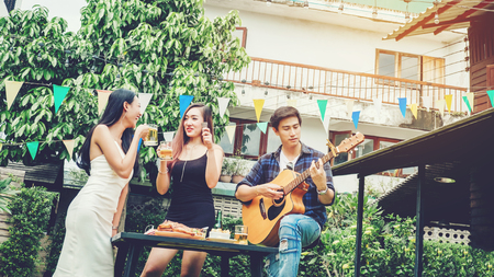Group of young asian people happy while enjoying garden party and play guitar on garden homeの写真素材