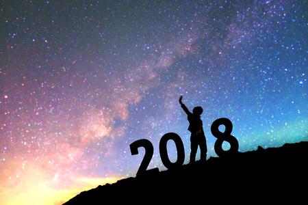 Silhouette young man Happy for 2018 new year background on  the Milky Way galaxy pointing on a bright star. dark sky tone . Vintage grain tone.の写真素材