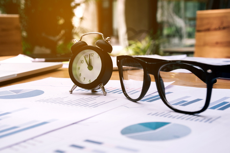 Glasses and clock on the business paper. Report chartの写真素材
