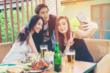 Group of friends are taking selfie and eating food are happy enjoying in homeの写真素材