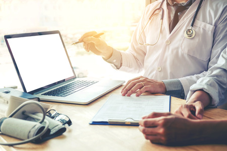 Doctor consulting with patient presenting results on blank Screen tablet computer sitting at tableの写真素材