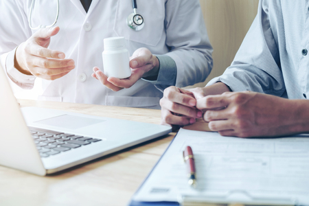 Doctor or physician recommend pills medical prescription to male Patientの写真素材