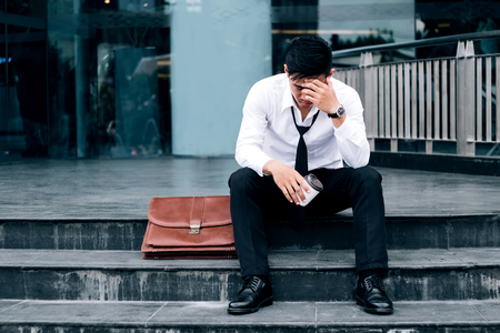 Unemployed Tired or stressed businessman sitting on the walkway after work Stressed businessman conceptの写真素材