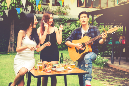 Group of young asian people happy while enjoying garden party and play guitar on garden homeの写真素材