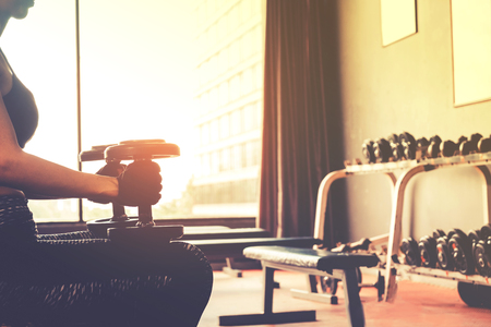 Asian sports woman doing exercises with dumbbell weights in gymの写真素材
