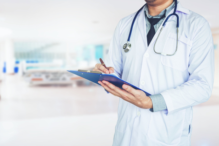 Doctor holding clipboard and stethoscope on background of Hospital wardの写真素材