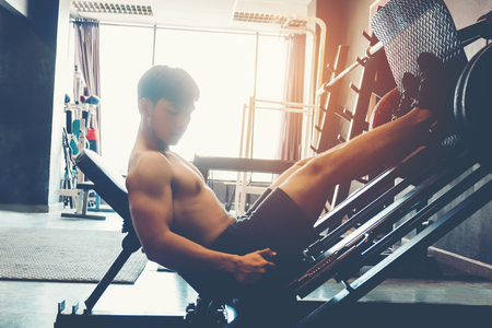 Fitness young man exercising using rowing machine in the gymの写真素材