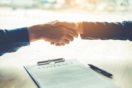 Business people negotiating a contract handshake between two colleaguesの写真素材